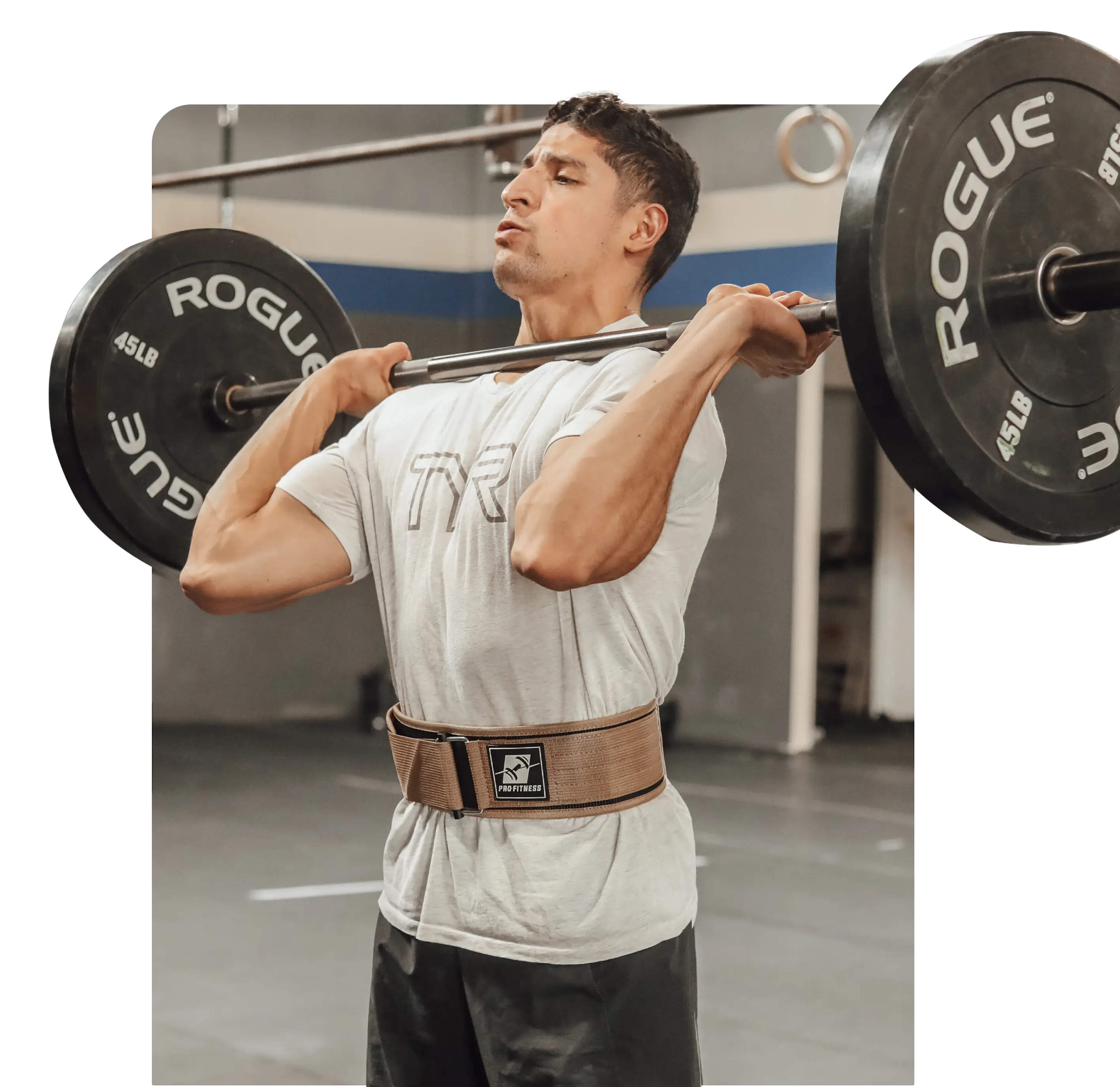 A man is lifting a barbell in a gym, wearing a weightlifting belt.